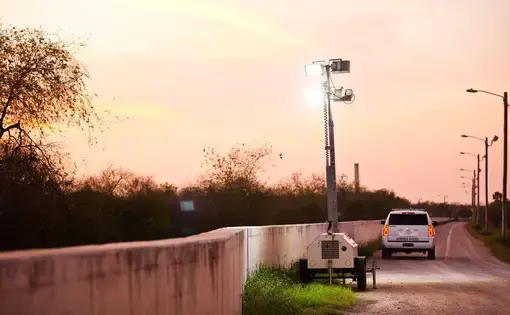 At dusk, Border Patrol agents place mobile floodlights along the levee-fence in Hidalgo County. Image by Callie Richmond. United States.