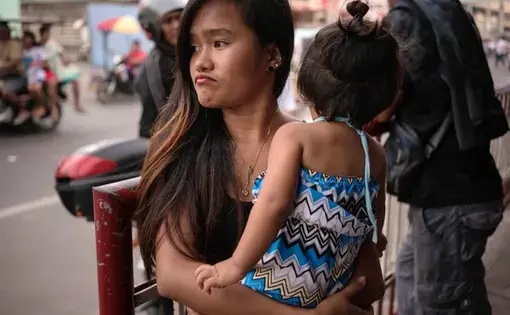 Jazmine Durana walks with her daughter Hazel in Navotas City, north of Manila, Philippines. Durana’s partner was killed a year ago by masked men. Image by Martin San Diego. Philippines, 2017.