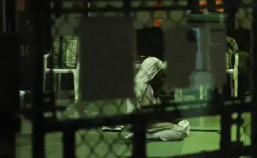 A detainee kneels in prayer at sunset on February 11, 2017, at Camp Six at Guantánamo’s Detention Center Zone. The military approved release of this photo. Image courtesy of Emily Michot/McClatchy. Cuba, 2019.