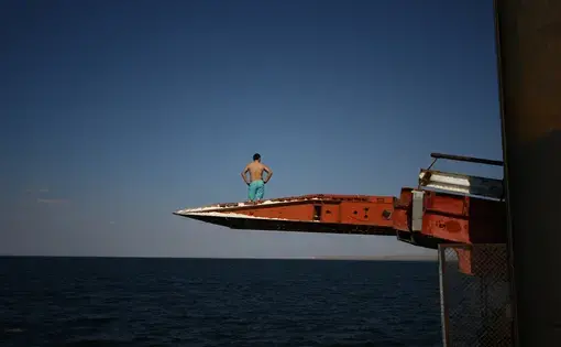 A man prepares to dive off a pier into the Caspian Sea in Sarytas, Kazakhstan, next to the spot where Russian geographers have determined is the true Europe–Asia border. Image by Joshua Kucera. Kazakhstan, 2016.