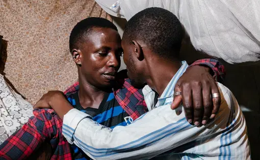 Sweet Love (left), a transgender woman, poses for a portrait in the Children of the Sun safe house with her partner of two years, Kenneth. Image by Jake Naughton. Uganda, 2017.