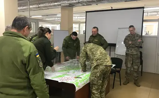Wisconsin National Guard Col. John Oakley, at right, watches Ukrainian soldiers prepare for a war game at a combat training center in western Ukraine. Oakley is commander of a unit of 164 Wisconsin soldiers who are mentoring Ukrainian military trainers. Image by Meg Jones / Milwaukee Journal Sentinel. Ukraine, 2020.
