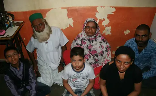 Shamin Ansari, 14 (left) lives with his brother, parents, and grandparents in a one-room flat in Shivaji Nagar. Born with intellectual disabilities, Shamin’s family worked with Apnalaya, a local NGO, to obtain the government-issued disability certificate required for his admission into a special school. Image by Kate Petcosky-Kulkarni. Mumbai, India, 2016.