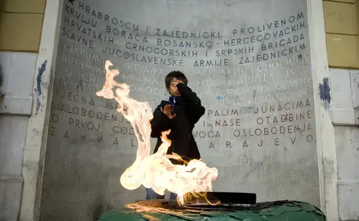A Roma child stands in front of the "Eternal Flame" in downtown Sarajevo, a memorial to the Sarajevan victims of World War II. The plaque does not mention the casualties of Sarajevan minorities. Image by Jasmin Brutus. Bosnia, July 2008. Media file: Danasharp_vjecna_vatra2.jpg