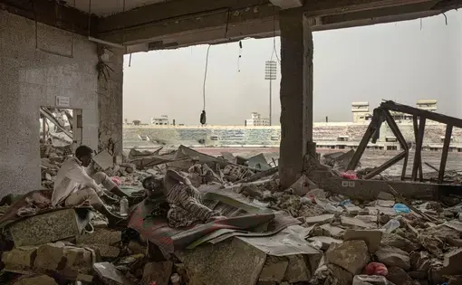 Ethiopian migrants take shelter in the "22nd May Soccer Stadium," destroyed by war, in Aden, Yemen. Image AP Photo/Nariman El-Mofty. Yemen, 2020.
