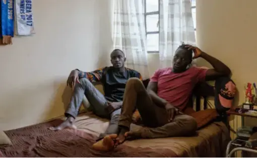 Collince Onyango, 27, left, and his brother Raphael Oduor, 24, right, both university students, in their home in Kibera, Nairobi, Kenya. Collince and his brother rent a single room from a resident who was lucky to move into the new houses that were built under the Kenya Slum Upgrading Project. Image by Peter DiCampo. 2018.