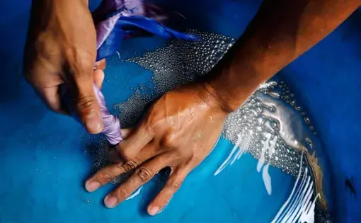 A young miner tends a ball mill beneath a Diwalwal home. Mercury in the blue pan is used during the process. Image by Larry C. Price. Philippines, 2013. Media file: price_diwalwal_edit_020.jpg