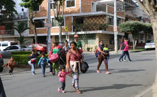 Venezuelan parents and children arrive at Fundación entre dos Tierras, one of the organizations providing aid to arriving migrants, in Bucaramanga, Colombia. At Fundación entre dos Tierras, volunteers serve migrants hot food and provide donations of clothing and other supplies. Image by Patrick Ammerman. Colombia, 2019.