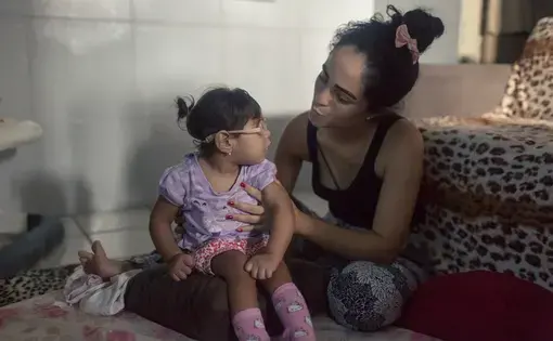 Mother and child: Dhulha Alen Silva do Nascimento and her daughter, Valentina, share a quiet moment at home. Image by&nbsp;Fábio Erdos. Brazil, 2017.