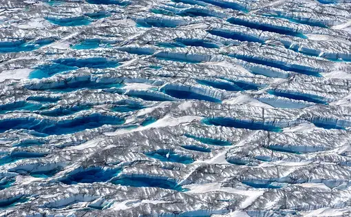 Meltwater fills bus-sized fractures near the edge of the Greenland Ice Sheet, while dust and algae darken adjacent ice. Image by Eli Kintisch. Greenland, 2017.