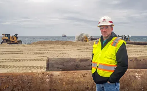 Jason Shea is the project manager for the beach renourishment initiative at Sea Bright. The dredge ship Magdalen is on the horizon. Image courtesy of NJ Spotlight. United States, undated.