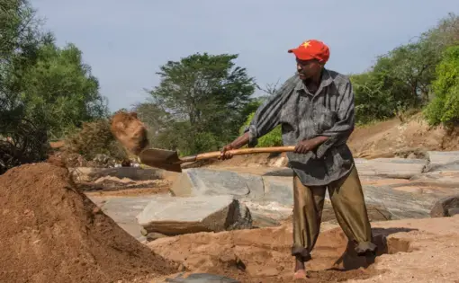 A man harvests sand in Makueni. Sand mining has drastically changed the ecosystem across the county. Image by Rachel Reed/Harriet Constable. Kenya, 2015.