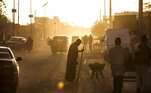 A man sweeps dust off the street at dusk in Agadez, Niger, January 16, 2018. Image by Joe Penney. Niger, 2018.