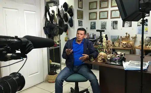 Forensic criminologist Israel Ticas speaks to media in the San Salvador office where he keeps grisly mementos from the crime scenes he has worked. Image by Jason Motlagh.