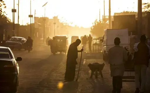 A man sweeps dust off the street at dusk in Agadez, Niger, January 16, 2018. Image by Joe Penney. Niger, 2018. A man sweeps dust off the street at dusk in Agadez, Niger, January 16, 2018. Image by Joe Penney. Niger, 2018.