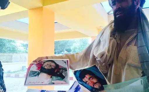 A man holds photographs of his and others' family members, victims of Abdul Hakim Shujayi, a US-funded militia commander in Uruzgan, Afghanistan.