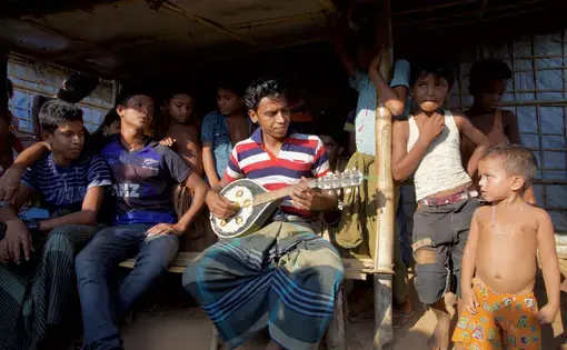 Musician holding a mandolin, surrounded by listeners. Image by Faiham Ebna Sharif. Bangladesh, 2019.