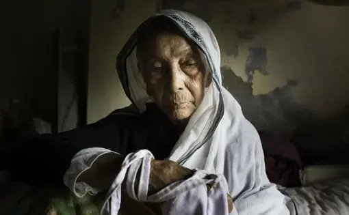 An elderly widow in her bed at Tarash Mandir, a short-stay home for young women and permanent facility for elderly widows in Vrindavan, India. This is the first and oldest home for widows in Vrindavan. Image by Amy Toensing. India, 2016.
