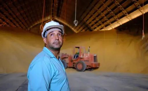 A worker at Grupo Vale do Verde looks on as grain is moved at one of its many facilities in the state of Mato Grosso. Big Ag in Brazil wants to see better transport options, including the construction of a railway, the Ferrogrão — “the grain train” — that would cut across the jungle. Image by Melissa Chan. Brazil, 2019.