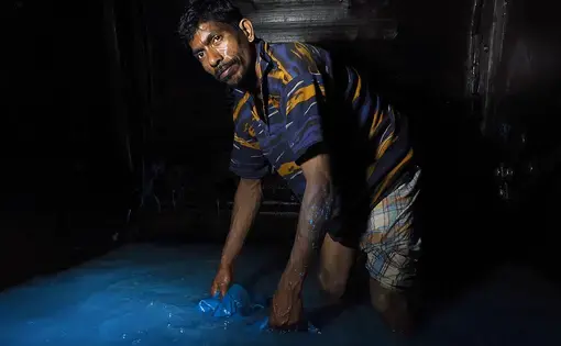 A barefoot worker stands inside an 8-foot tall-tumbling drum filled with chromium (III) sulfate and other chemicals. Workers often have to crawl inside the drums to remove hides. Image by Larry C. Price. Bangladesh, 2016.