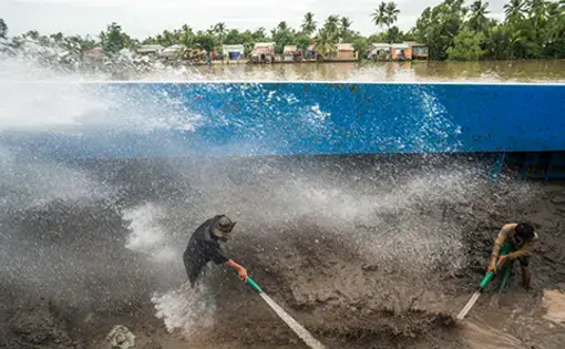 Sand barge workers near Can Tho City hose down a mountain of sand pumped up from branches of the Mekong. The wet sand is then pumped through underground pipes to a road construction site further inland.