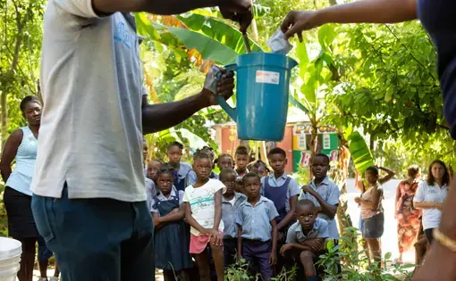 School children near Mirebalais are shown how to mix oral rehydration solution as part of an effort to head off any recurrence of cholera in Haiti. Image by Allison Shelley. Haiti, 2020.