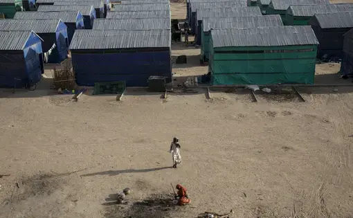 A young woman walks through Custom House, a large IDP camp on the outskirts of Maiduguri that is home to over 9,000 people. There are more than 1.7 million displaced in Northern Nigeria alone, and the number of shelters at refugee camps does not meet the needs of the huge population. The camps that do exist are often cut off from town and markets and frequent sites of suicide bombs. Image by Sarah A. Topol. Nigeria, 2017.