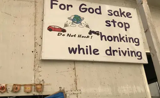 An anti-honking sign hangs on the wall at the Earth Saviours Foundation just outside New Delhi. The foundation is active in caring for the homeless and several environmental causes, including noise pollution. Image by Chris Berdik. India, undated.