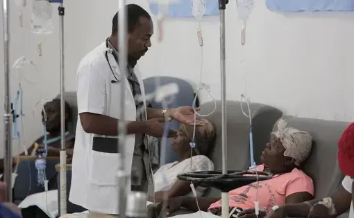 A physician talks to Paula Paul as she gets hydration before chemotherapy at the University Hospital of Mirebalais in central Haiti. Image by José A. Iglesias. Haiti, 2018.