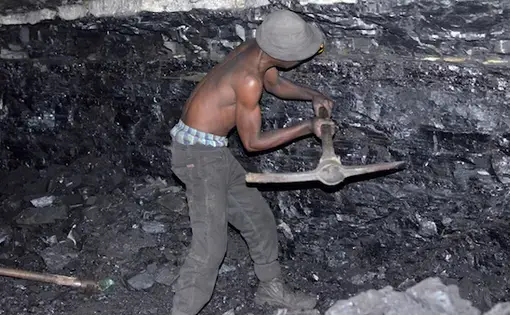 A small-scale miner illegally digs coal from an abandoned, former Anker Coal operation just outside Ermelo, Mpumalanga. Image by Mark Olalde. South Africa, 2017.