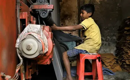 A 10-year-old boy pulls a hide from pressing machine at a tannery in Dhaka, the capital of Bangladesh. Image by Justin Kenny. Bangladesh, 2016.
