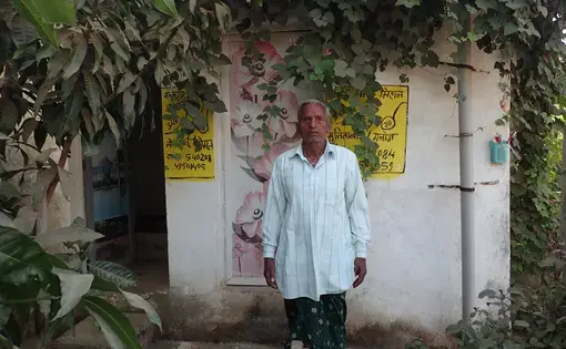 In Pihrid, a villager stands in front of two latrines he was ordered to construct as part of a government sanitation scheme. Each latrine cost Rs 50,000, or about $770. Image by Yardain Amron. India, 2017.
