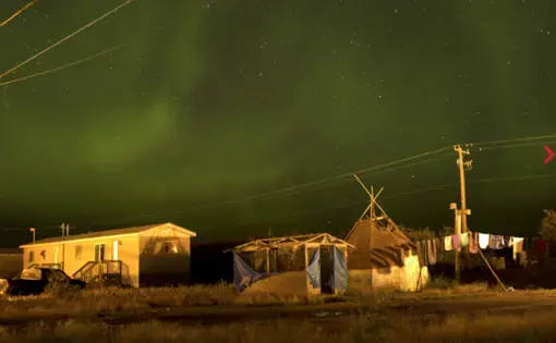 The northern lights fill the sky over the remote First Nations community of Attawapiskat. Attawapiskat is an isolated First Nation community located in northern Ontario, Canada, at the mouth of the Attawapiskat River on James Bay. On April 9, 2016, the community of approximately 2000 people declared a state of emergency after being overwhelmed with attempted suicides, over 100 attempts in a ten month period. Image by David Maurice Smith/Oculi. Canada, 2016.