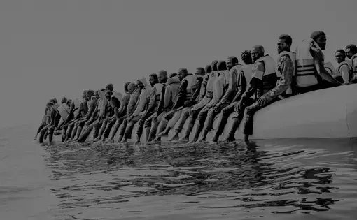 Roughly a hundred and fifty people wait to be rescued from an inflatable dinghy in the Mediterranean Sea, twenty miles north of Libya. The boat left with only enough fuel to reach international waters. Image by Ben Taub. Libya, 2016.