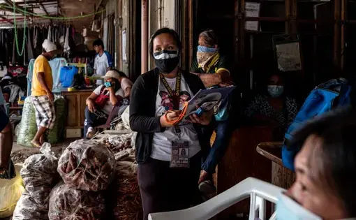 Filipina nurse April Abrias in a crowded vegetable market while checking on patients showing symptoms of Covid-19. Image by Xyza Cruz Bacani. Philippines, 2020.