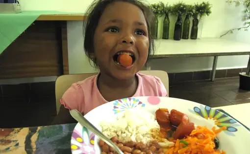 A child in Sao Paulo eats lunch provided at her day care. This meal is part of Brazil's National School Feeding Program (PNAE), which feeds 43 million children. Image by Rhitu Chatterjee. Brazil, 2015. Media file: brazil_039.jpg