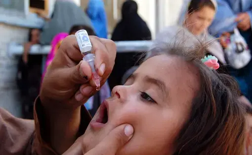 Health worker administrates polio-vaccine drops to a child during anti-polio immunization campaign at Pak-Afghan Border on April 08, 2015 in Chaman. Image by Shutterstock. Pakistan, 2015.
