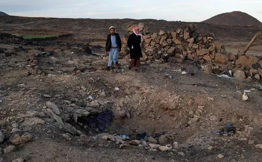 Jamal Muhammad Ali Qied (left), whose 14-year-old brother was killed in the airstrike, and Yahia al-Abdeli, who was injured and whose brother was killed, at the site of the attack. Image by Tyler Hicks/The New York Times. Yemen, 2018.