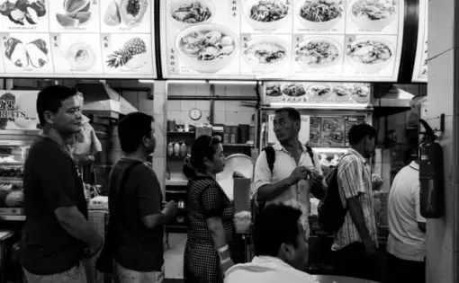 Xi Feng stands in the line with other Chinese migrant workers to get free meal. Image by Xyza Bacani. Singapore, 2017.