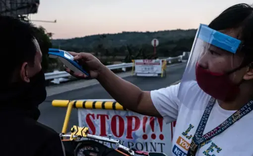 Rose Ann, a rural nurse, checks the temperature of a traveler at a checkpoint. Image by Xyza Bacani. Philippines, 2020.