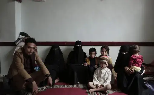 A family poses for a photograph in their room at a shelter for displaced persons in Ibb. Image by Nariman El-Mofty/AP Photo. Yemen, 2018.