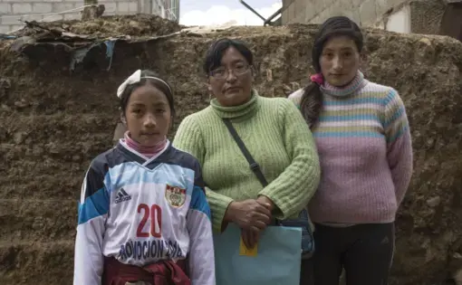 Sunmi (left) and Máyori (right) with their mother in their home. Sunmi was diagnosed by the Health Ministry in September 2015 with developmental disabilities, learning disability and chronic epistaxis (nosebleeds) from high levels of lead in her bloodstream. Image by Ricardo Martínez. Peru, 2017.