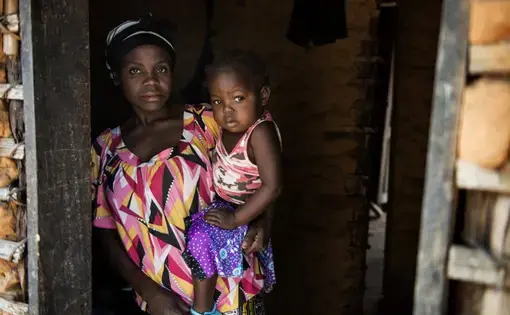 Olga, 30, with her 3 year old daughter Odile in Kahemba. Roughly a year ago Odile stopped moving her legs, Olga is not sure why she became paralyzed but had been feeding her a diet consisting largely of various forms of cassava. Image by Neil Brandvold. DRC, 2016.