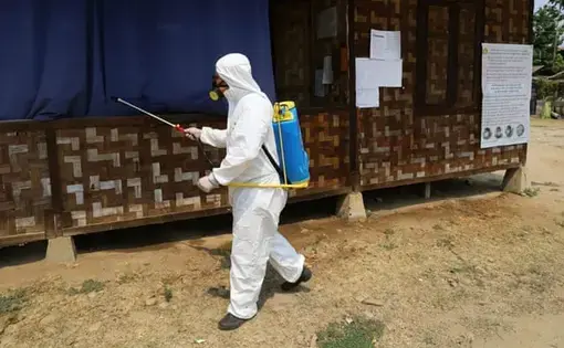 A volunteer from the Kachin State COVID-19 Prevention network sprays disinfectant at a camp in Myitkyina, Kachin state. Image courtesy Al Jazeera. Myanmar, 2020.