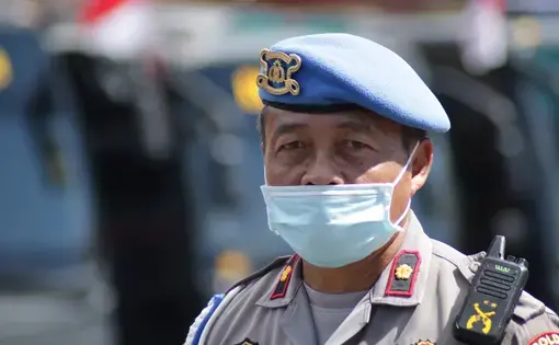 An Indonesian police officer wears a mask while on duty. Image by Herwin Bahar / Shutterstock. Indonesia, 2020.