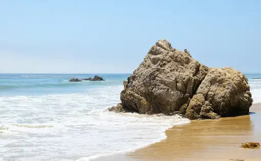 Rocks in the ocean on a sunny day at Broad Beach in Malibu, California. Image by Shutterstock. United States, undated.