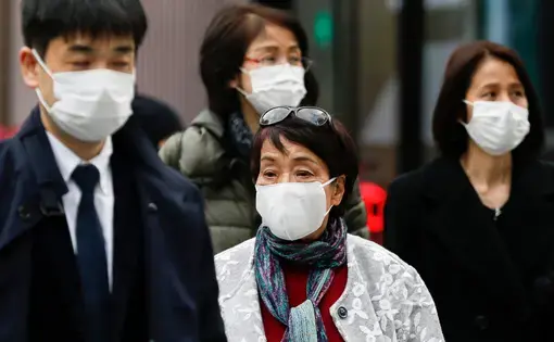 Pedestrians wearing surgical masks to prevent infectious diseases walk along the luxury area of Ginza. Japan has confirmed coronavirus infections cases in the country. Image by Shutterstock. Japan, 2020.
