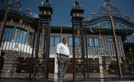 Rudi Dilip Sardjoe at the gates of his residential and office compound in Paramaribo, Suriname. Image by Stephanie Strasburg. Suriname, 2017.