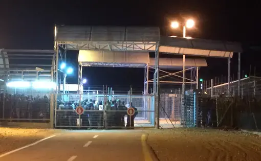 Palestinian men who labor in Israel wait to cross from the Palestinian to the Israeli side of the Eyal checkpoint before sunrise in February. Image by Miriam Berger. Israel, 2017. 