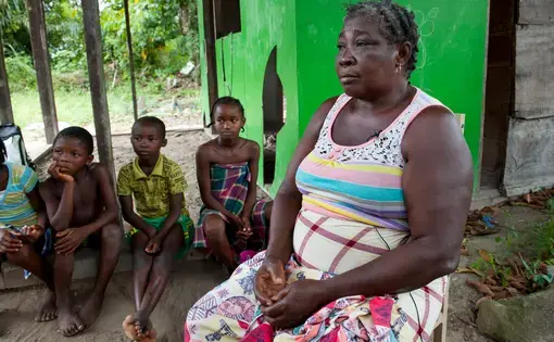Emelien Adjako sits for an interview in her village of Kajapaati along the Suriname River on Tuesday, March 14, 2017. Adjako was one of those from over 40 Saamaka villages displaced by the flood waters caused by the formation of a reservoir with the construction of the Afobaka Dam. Built by Suralco to power a now defunct aluminum smelter, the dam now provides about half of Surinam's electricity, none of which has reached Adjako's replacement home. Image by Stephanie Strasburg/Pittsburgh Post-Gazette…